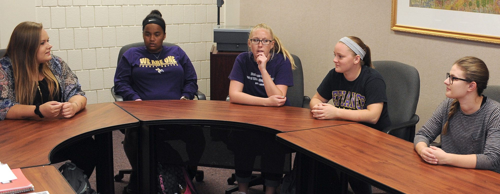 five students sitting around a horse shoe table having a discussion