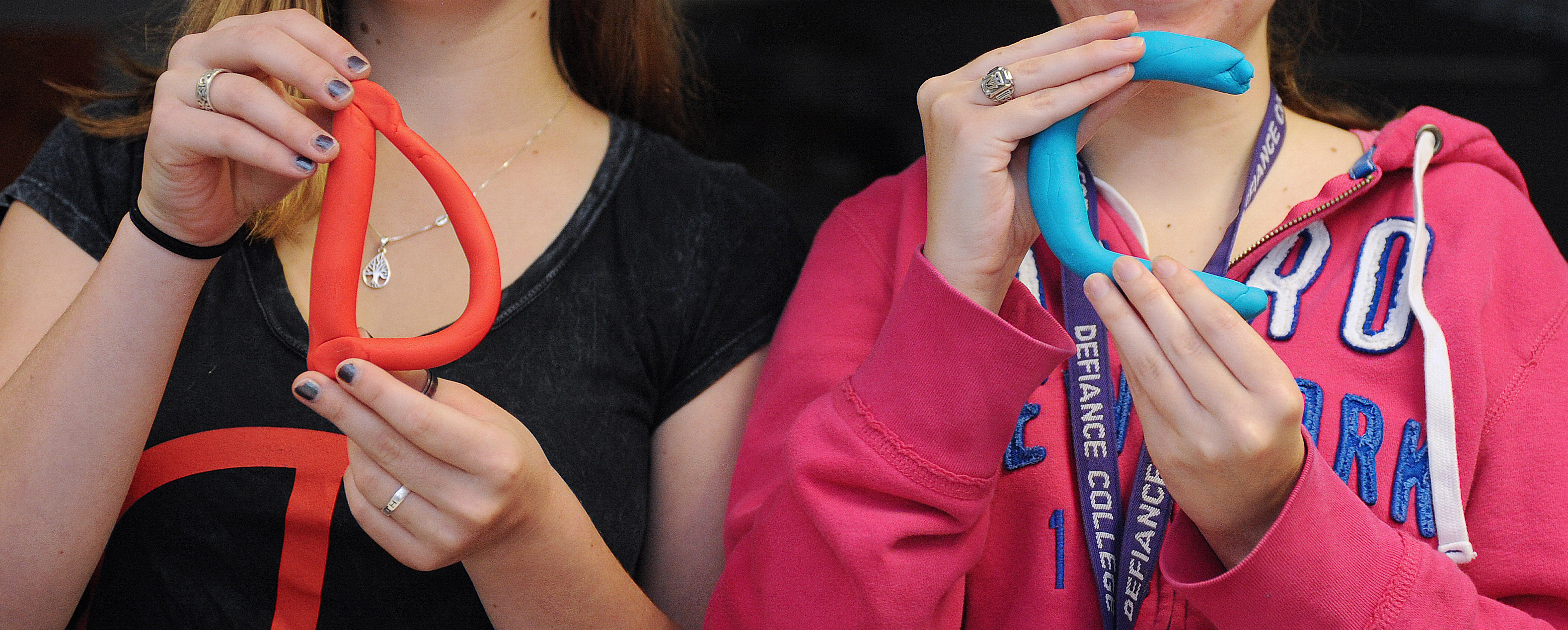 Close up of two students hands holding clay letters D and C.