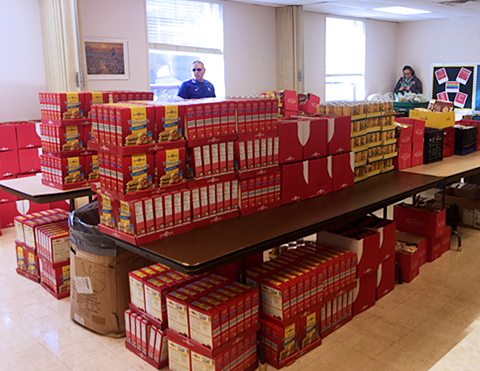 Two volunteers in room filled with boxes of food