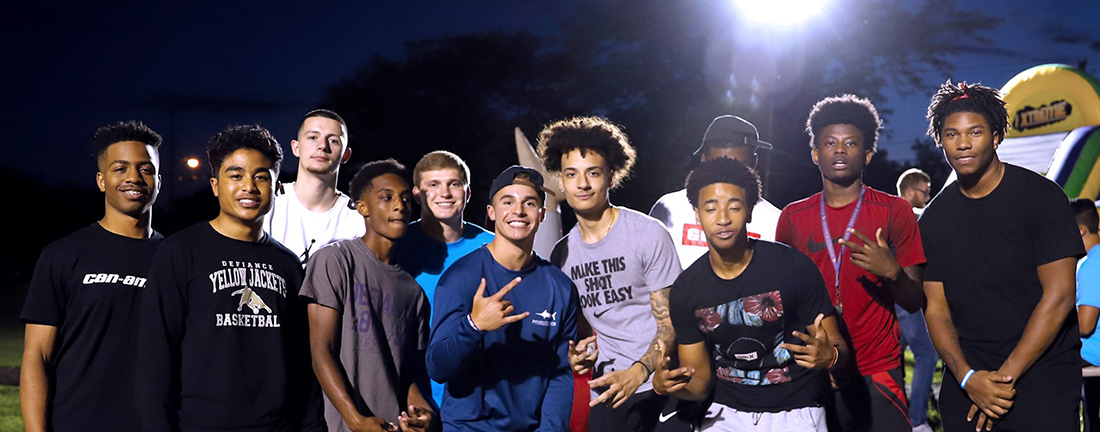 11 students standing in a line, posing and smiling for the camera