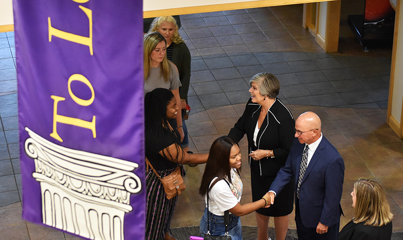 DC president mingling with students and shaking hands.